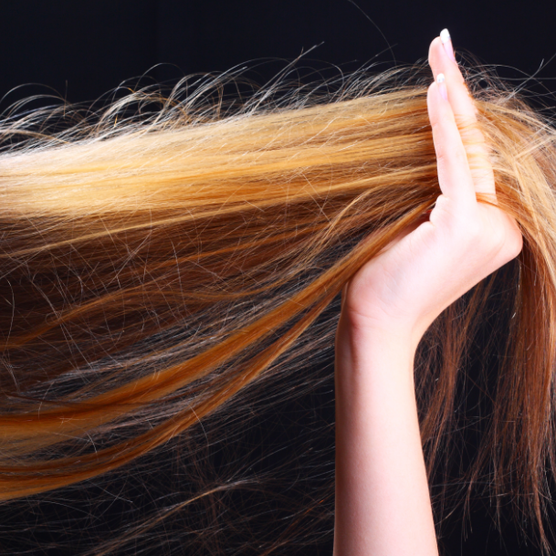 Woman's hand holding length of hair on black background