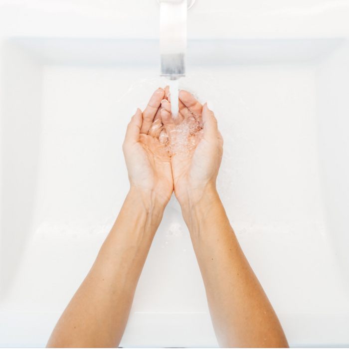 A woman's hands under running water in washroom