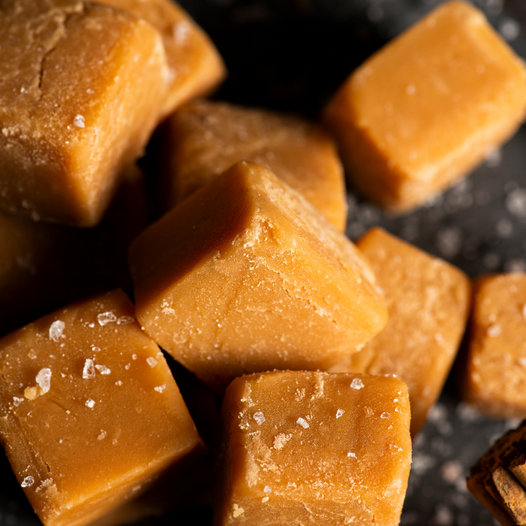 Close up of pumpkin fudge squares with stick of cinnamon in the corner.