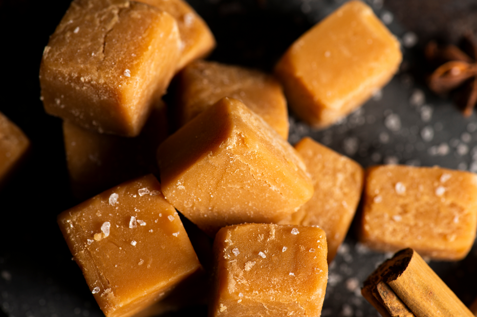 Close up of pumpkin fudge squares with stick of cinnamon in the corner.