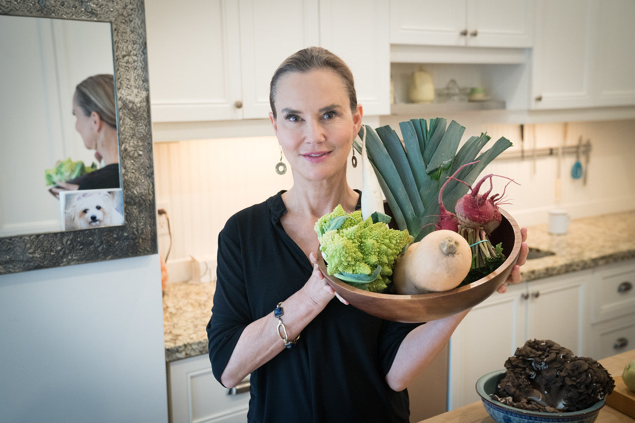 A woman with healthy skin holding a bowl of assorted vegetables