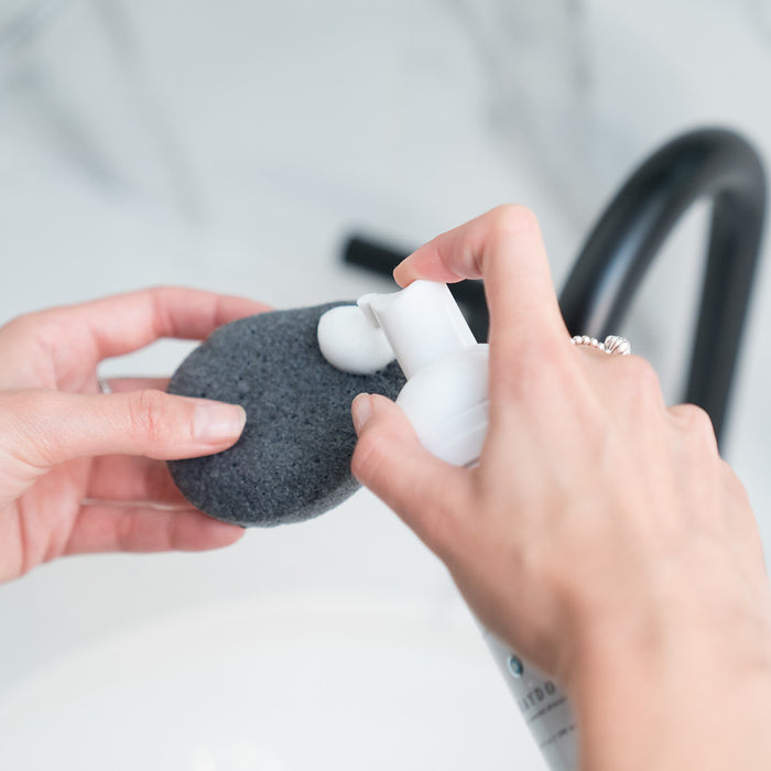 A fragrance-free foaming cleanser being dispensed on a bamboo charcoal konjac sponge. 