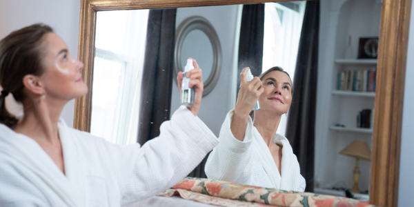 graydon moffat, founder of graydon skincare, wears a fuzzy robe and spritzes face food mineral mist on her face in the bathroom