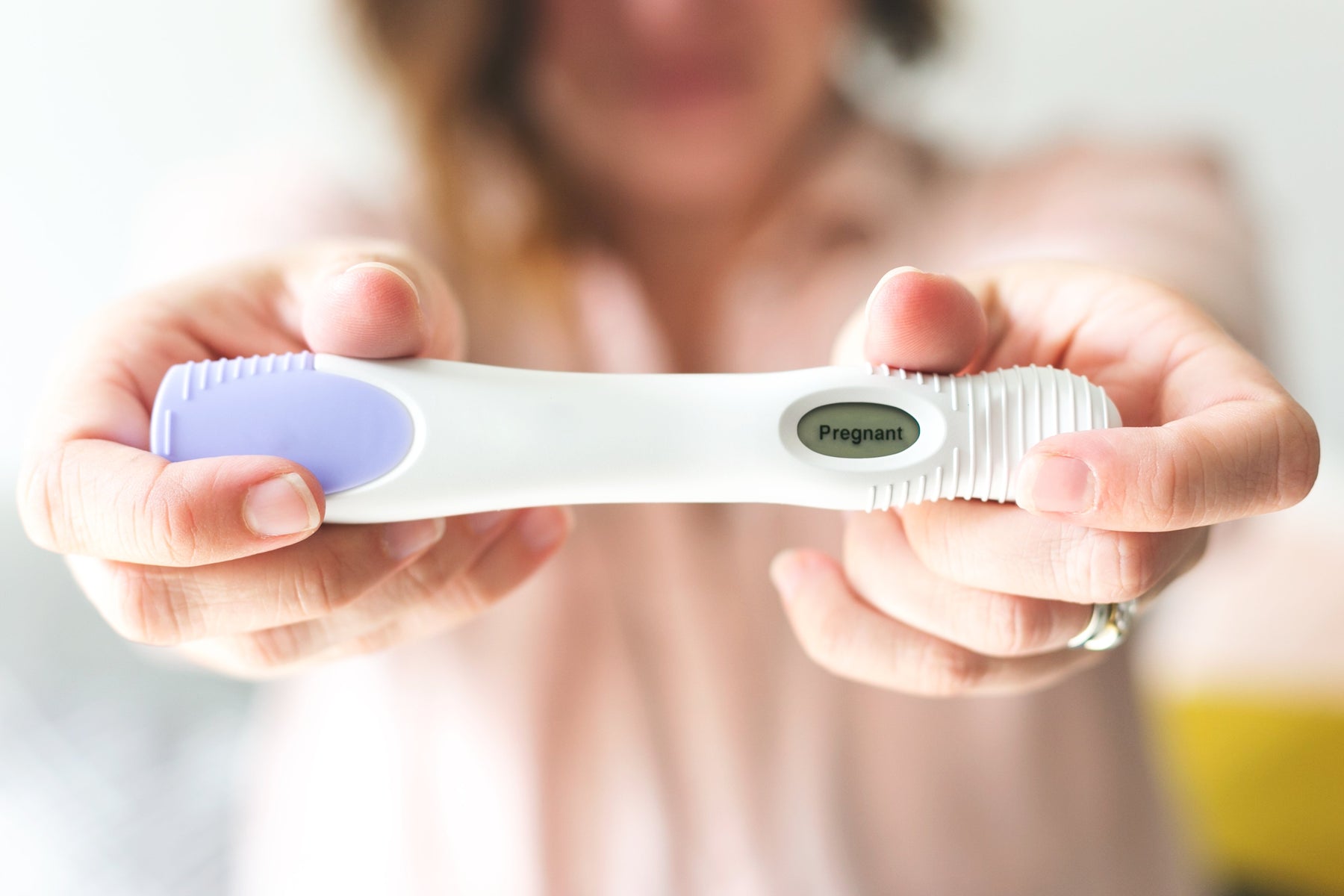 A woman holding a pregnancy test indicating "pregnant".