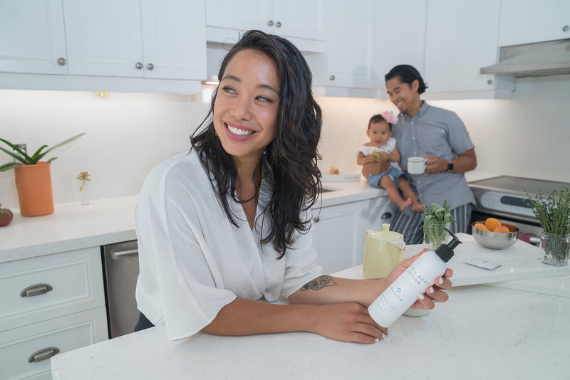 A woman holding a bottle of multipurpose face and body lotion for sensitive skin.